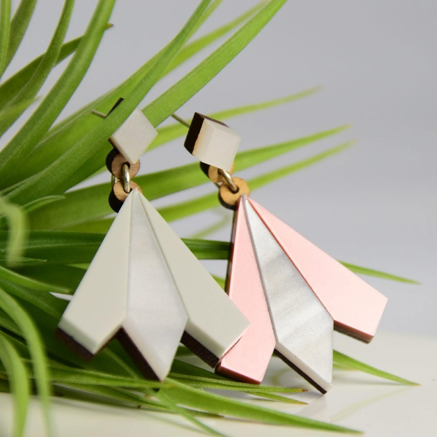 Geometric drop earrings in pink, grey and cream on a green plant